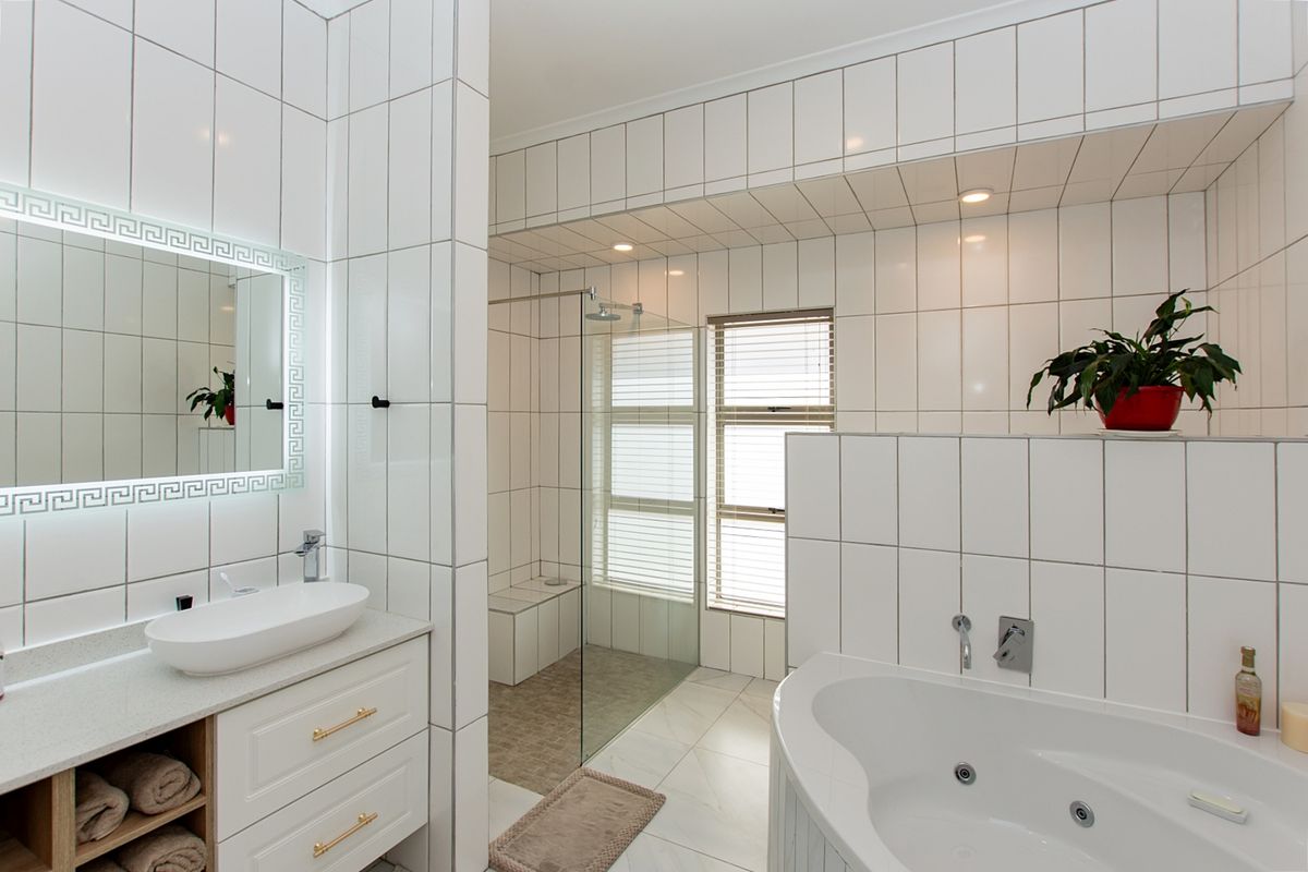 Modern bathroom featuring a vessel sink vanity, a built-in jetted bathtub, and a spacious walk-in shower with floor-to-ceiling white tiling.