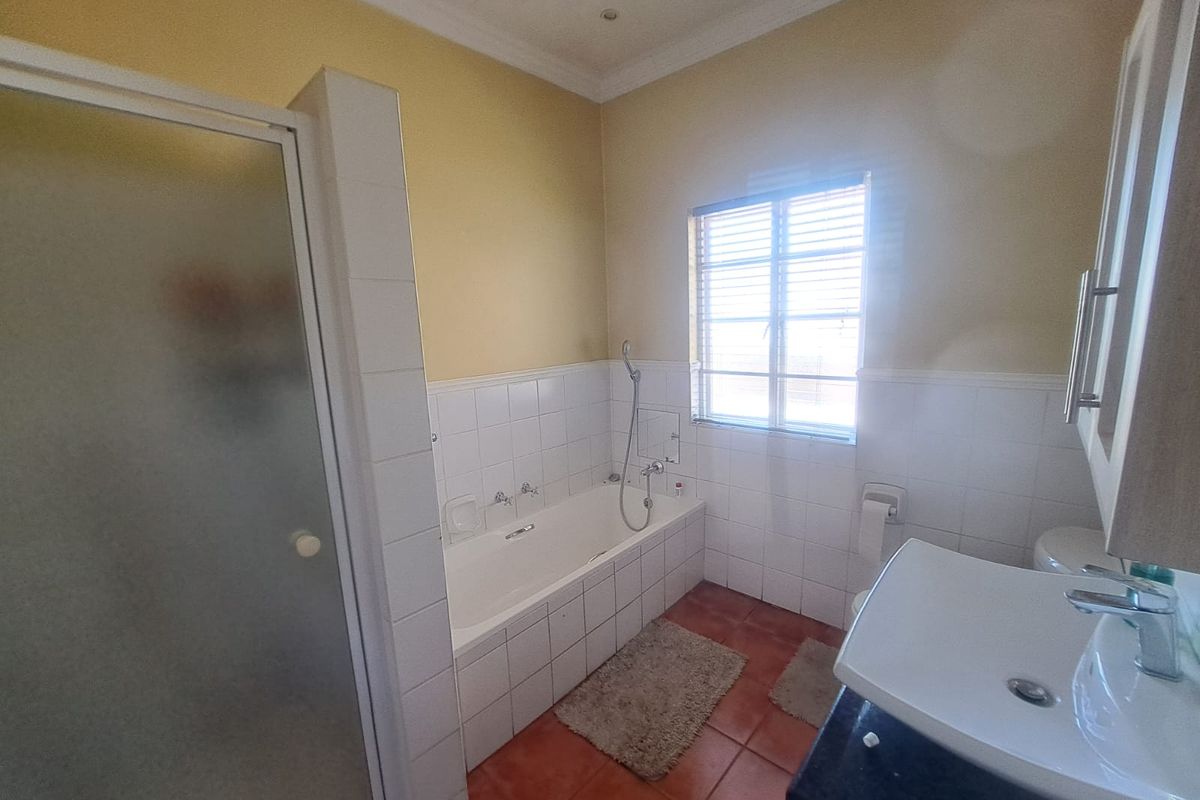 A functional bathroom featuring a built-in bathtub, separate shower enclosure, vanity basin, and toilet with tiled finishes.