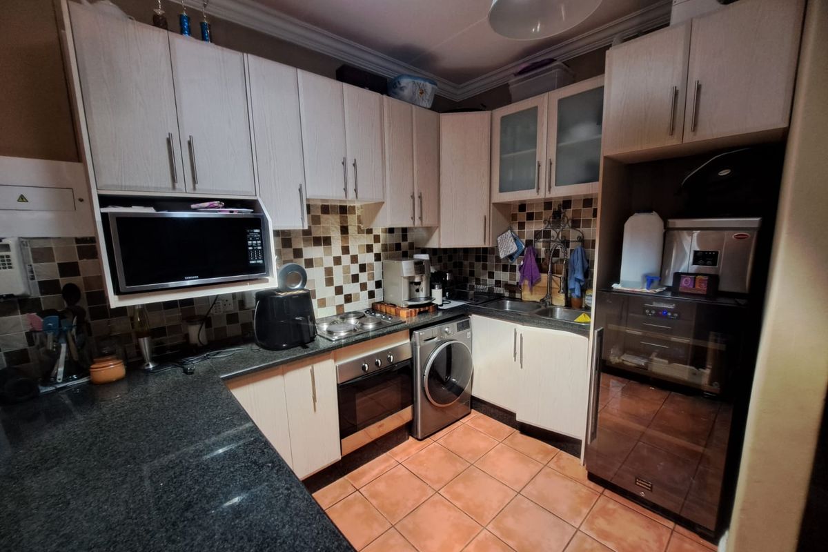 Compact kitchen featuring light wood cabinetry, granite countertops, mosaic tile backsplash, and integrated appliances including an oven and hob.