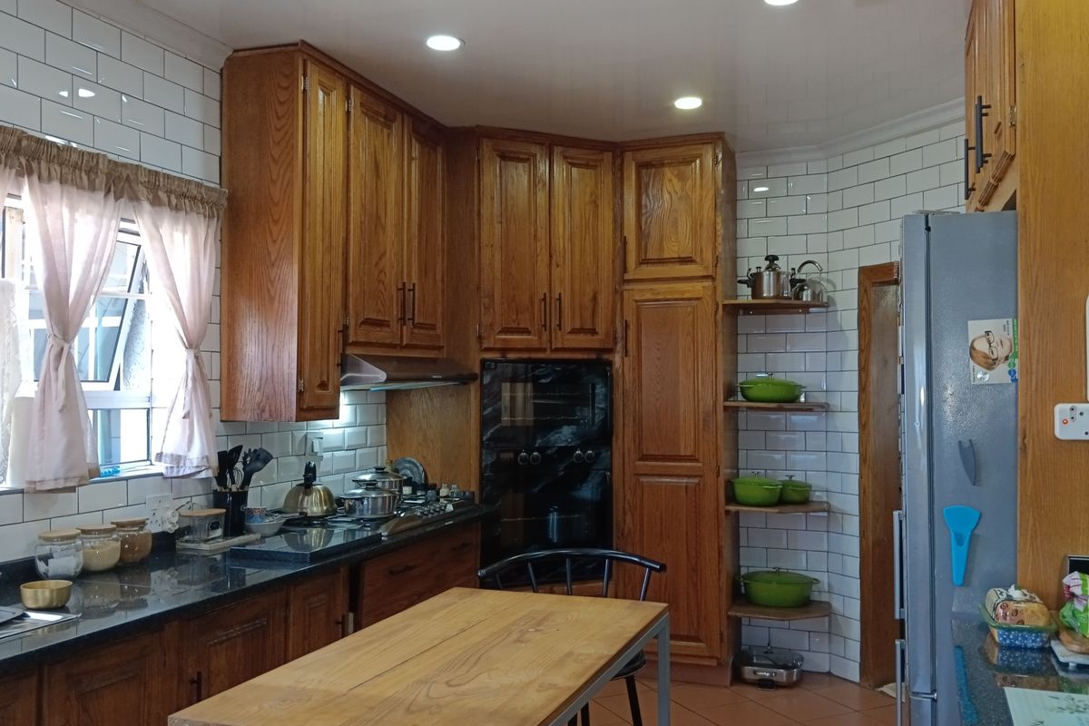 A functional kitchen featuring warm wooden cabinetry, subway tile backsplash, granite countertops, and built-in appliances including an oven and gas hob.