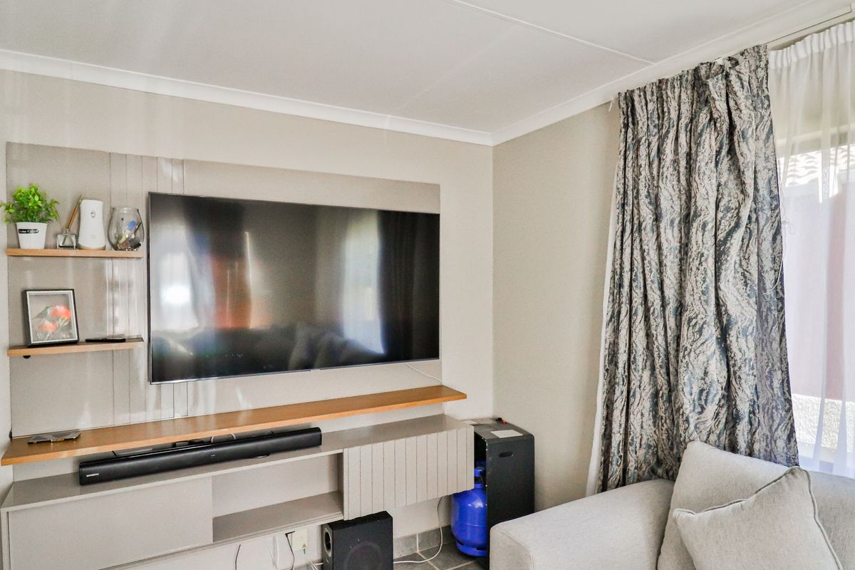 A living room featuring a modern built-in media console with floating shelving and neutral wall finishes.