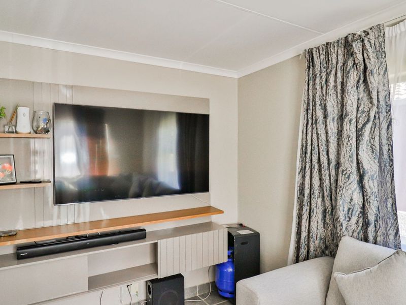 A living room featuring a modern built-in media console with floating shelving and neutral wall finishes.