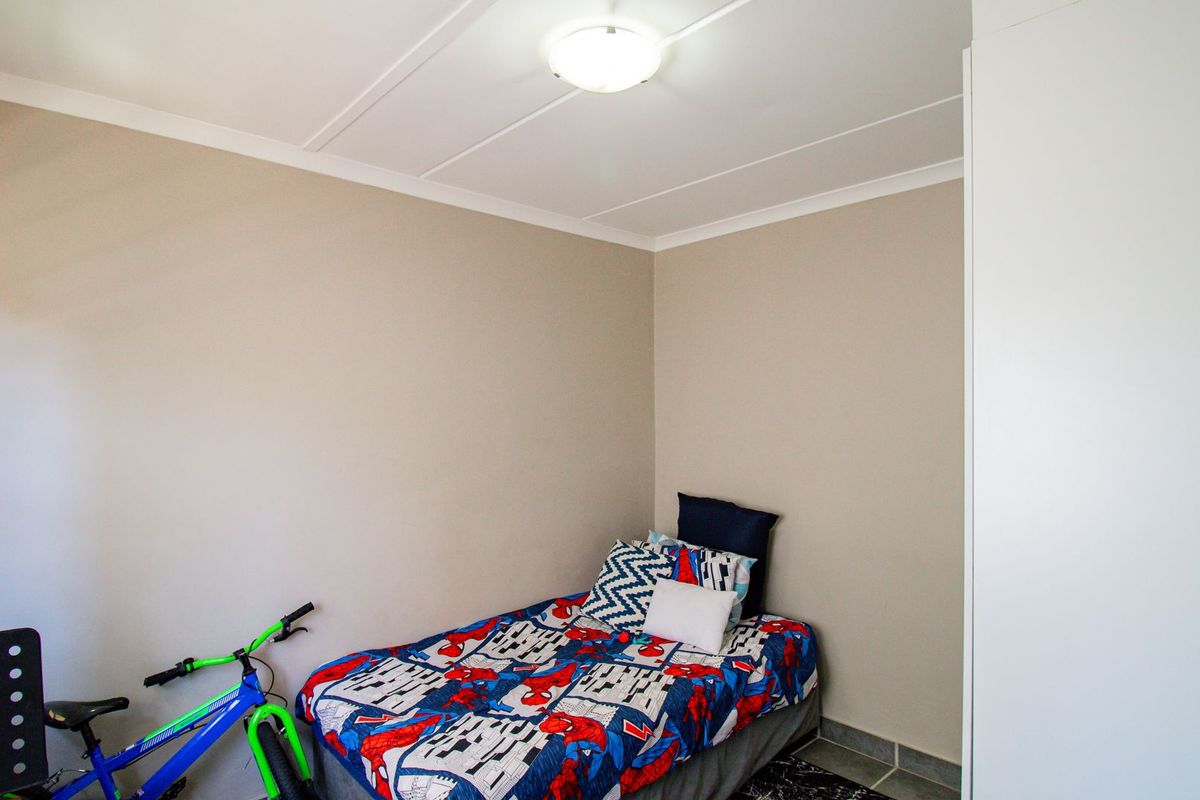 A functional bedroom featuring neutral wall finishes, a built-in wardrobe, and a central ceiling light fixture.