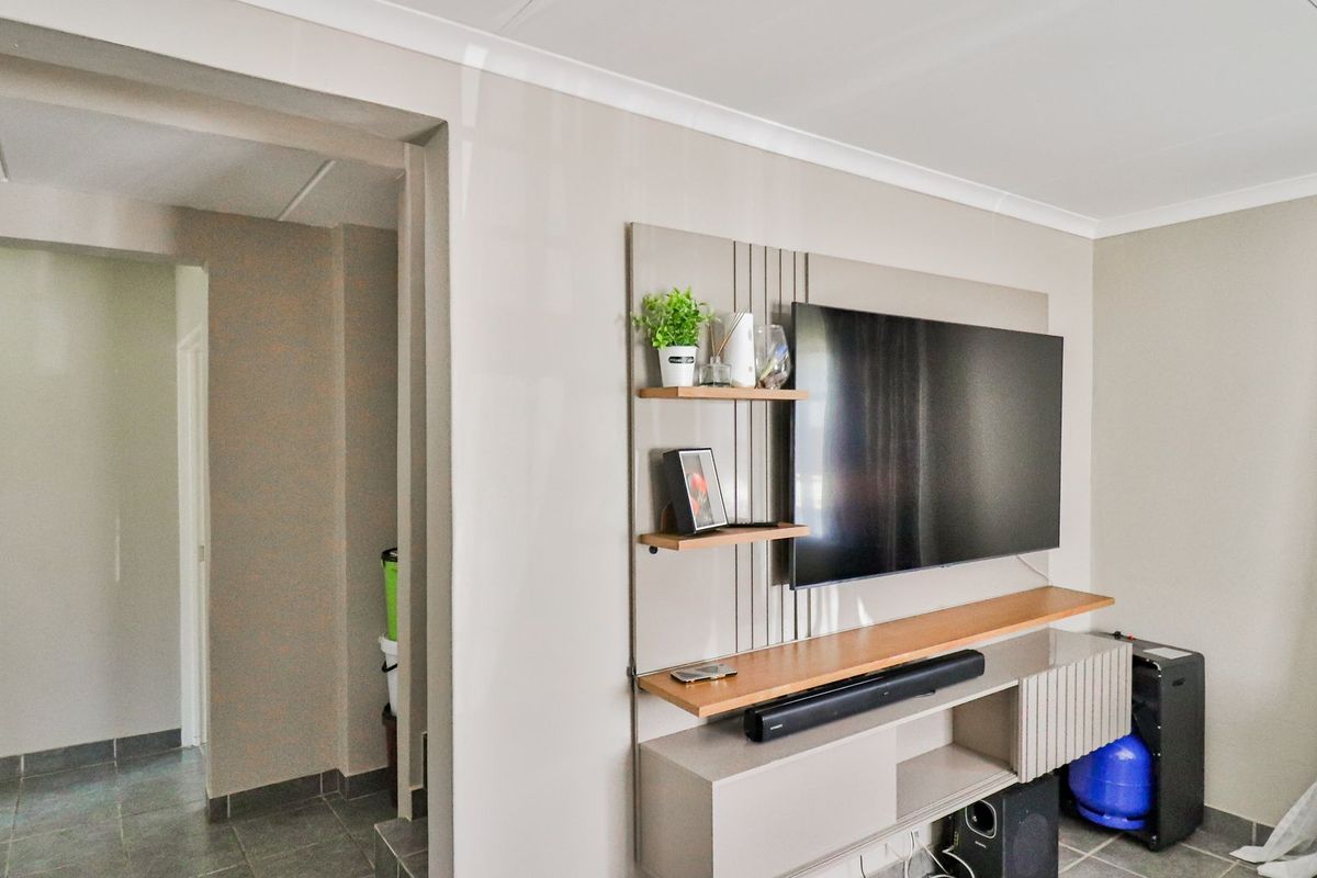 A well-maintained living room featuring a modern built-in media console, neutral wall tones, and tiled flooring throughout.