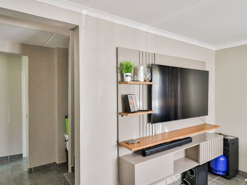 A well-maintained living room featuring a modern built-in media console, neutral wall tones, and tiled flooring throughout.