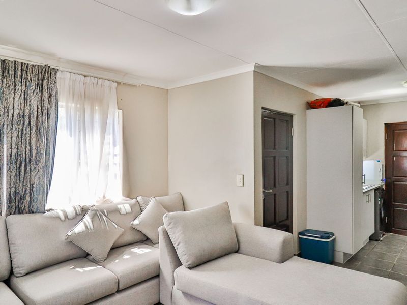 Open plan living area featuring tiled flooring, neutral walls, and direct access to adjacent kitchen and utility spaces.