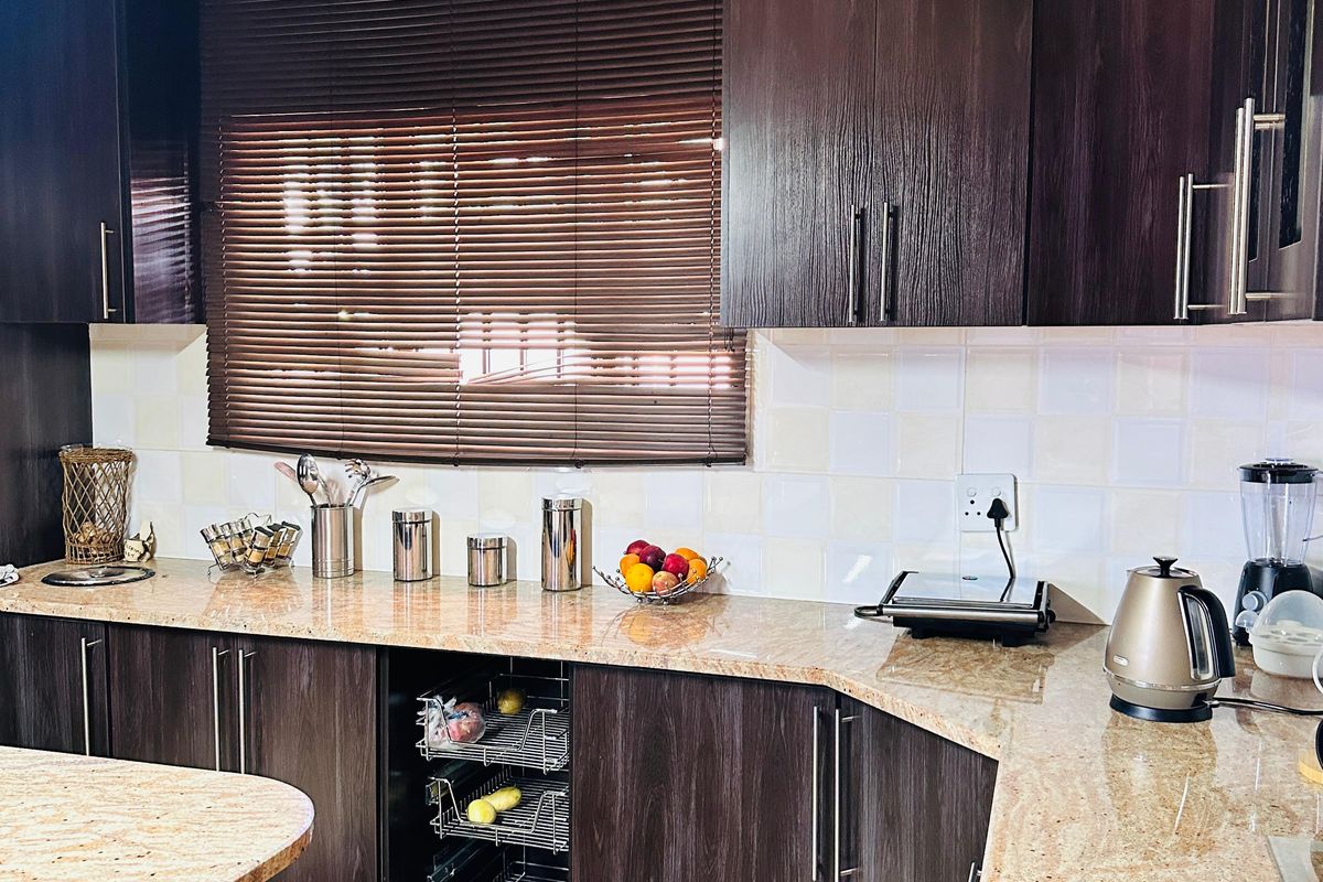 A well-maintained kitchen featuring dark wood cabinetry, granite countertops, a tiled backsplash, and recessed lighting with crown molding details.