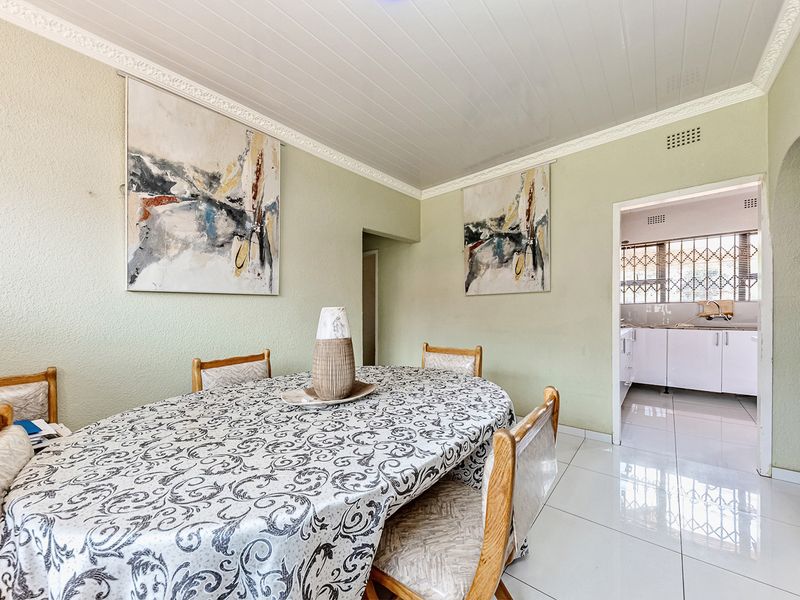 Dining room featuring tiled flooring, decorative crown molding, and an open archway leading to the kitchen area.
