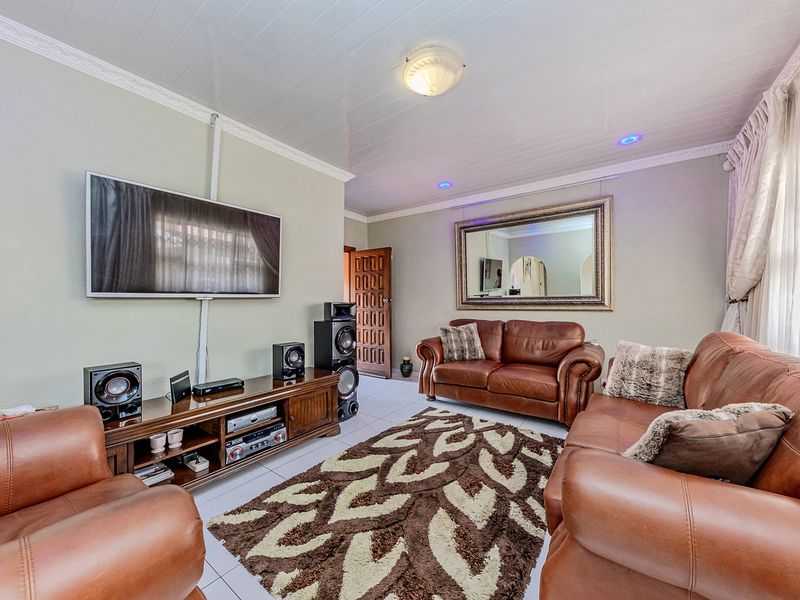 A comfortable living room featuring tiled flooring, coved ceilings, and recessed lighting, providing a functional and well-lit space for relaxation.