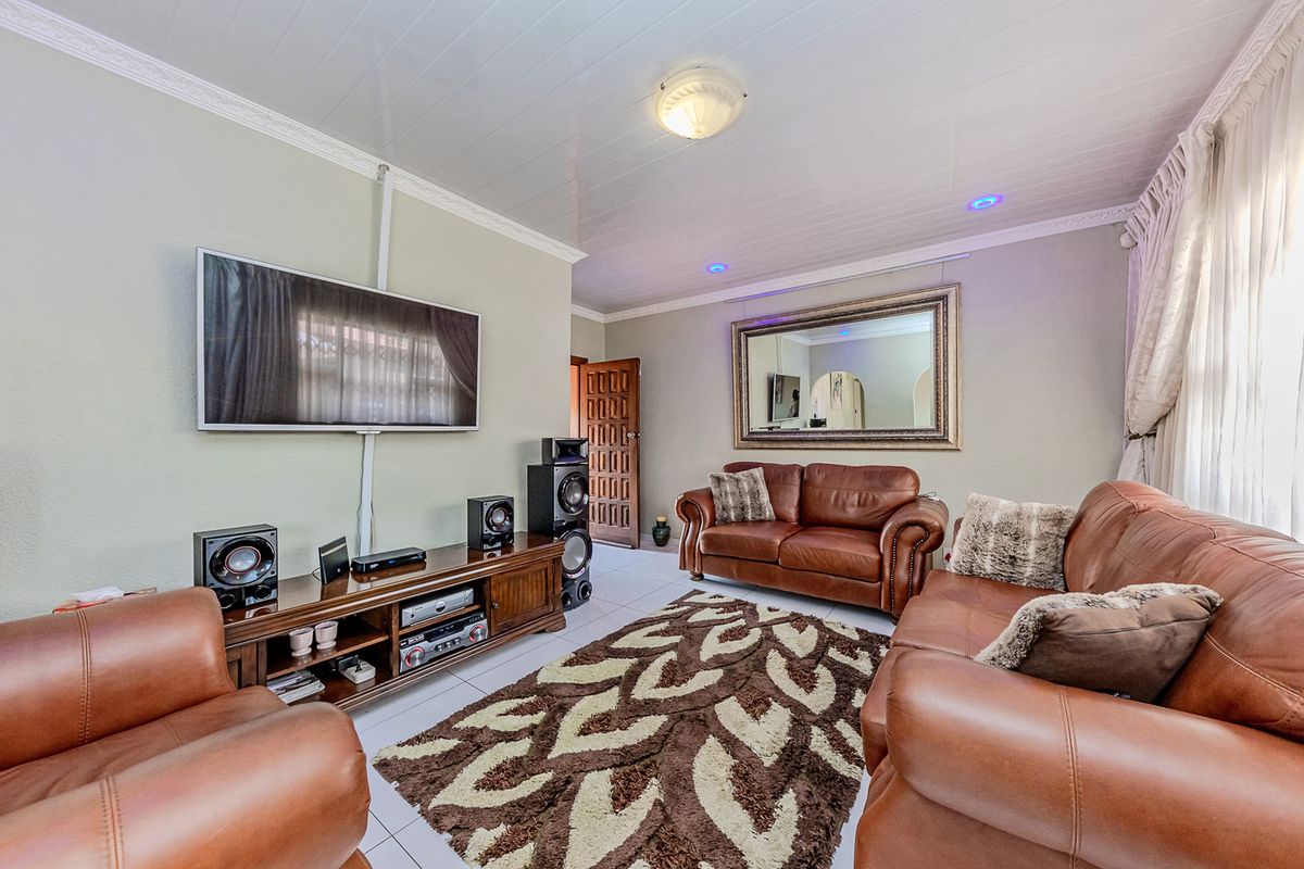 A comfortable living room featuring tiled flooring, coved ceilings, and recessed lighting, providing a functional and well-lit space for relaxation.