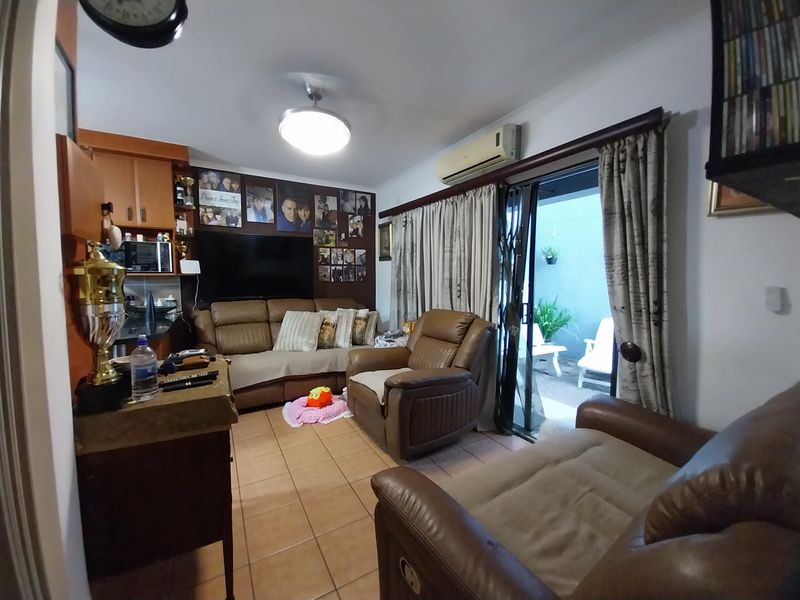 A living room featuring tiled flooring, a wall-mounted air conditioning unit, and a sliding glass door providing access to an outdoor patio area.