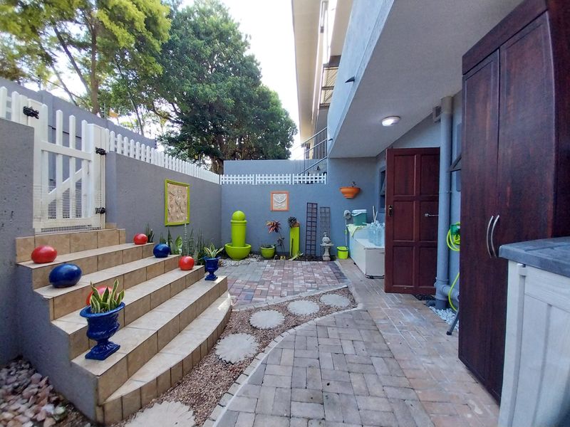 A private rear courtyard featuring paved pathways, tiled steps, and secure boundary walls, providing a functional outdoor space for the apartment.