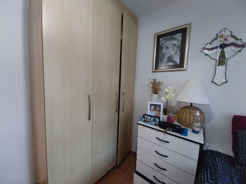A bedroom featuring a light wood-finish built-in wardrobe with modern metal handles.