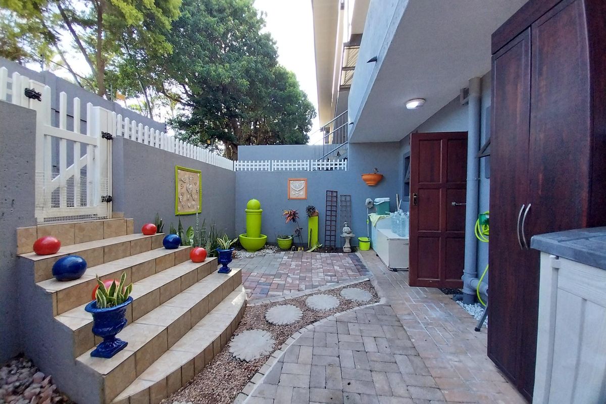 A private rear courtyard featuring paved pathways, tiled steps, and secure boundary walls, providing a functional outdoor space for the apartment.