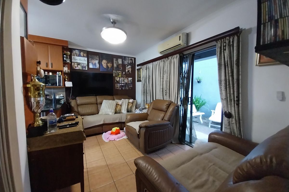 A living room featuring tiled flooring, a wall-mounted air conditioning unit, and a sliding glass door providing access to an outdoor patio area.