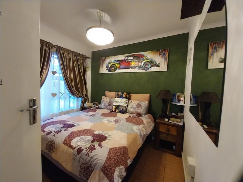 A cozy bedroom featuring tiled flooring, a feature wall, and a window fitted with security bars.
