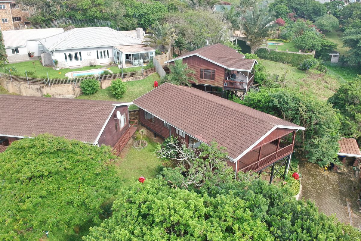 Aerial view of a townhouse complex featuring timber-clad structures with tiled roofs, elevated wooden decks, and surrounding lush garden landscaping.