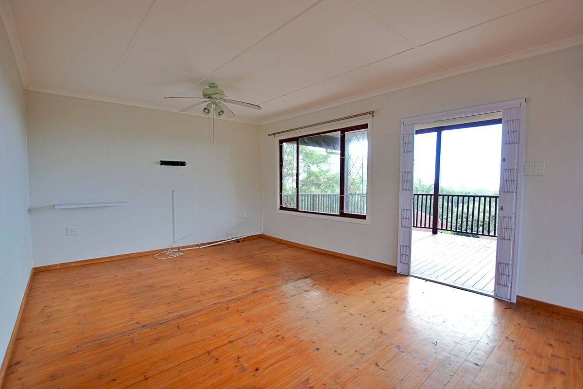 Spacious living area featuring polished timber flooring, a ceiling fan, and direct access to an outdoor balcony through a sliding door.