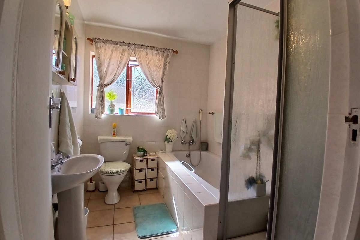 A functional bathroom featuring a pedestal basin, a standard toilet, and a combined bathtub and shower enclosure with tiled finishes.