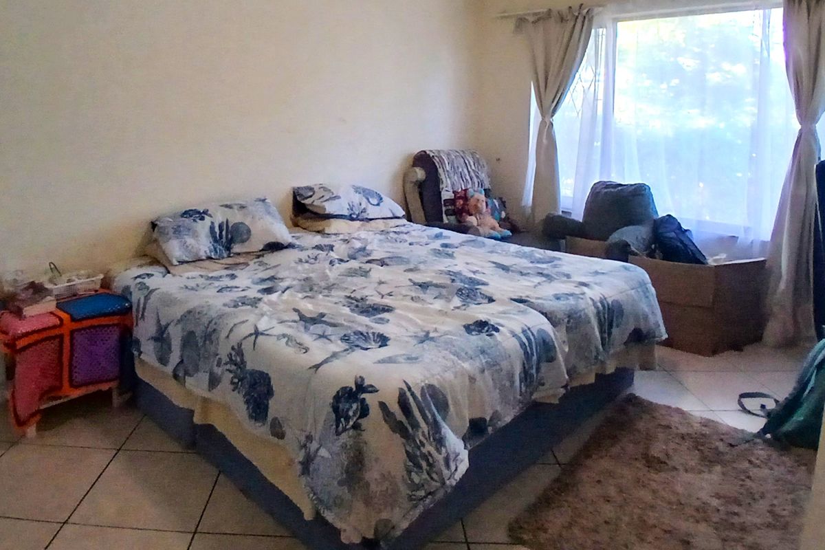 A bedroom featuring tiled flooring and a large window allowing natural light into the space.