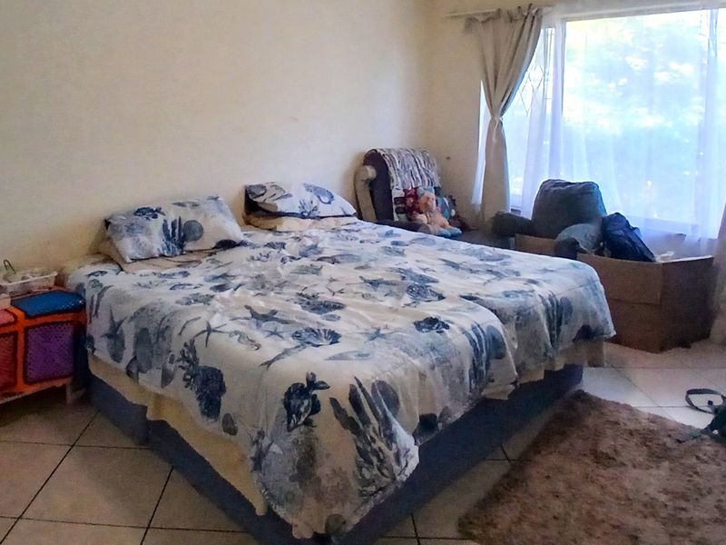 A bedroom featuring tiled flooring and a large window allowing natural light into the space.