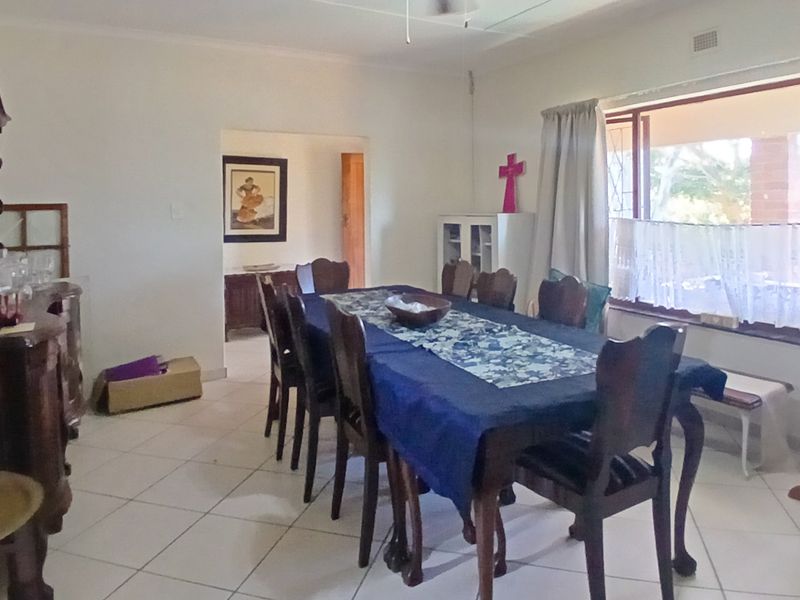 A spacious dining room featuring tiled flooring, a ceiling fan, and a large window allowing for natural light.