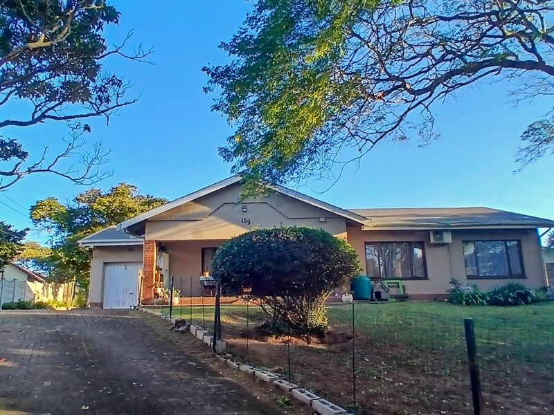 Front view of a single-story residential house featuring a paved driveway, single garage, and established garden area.