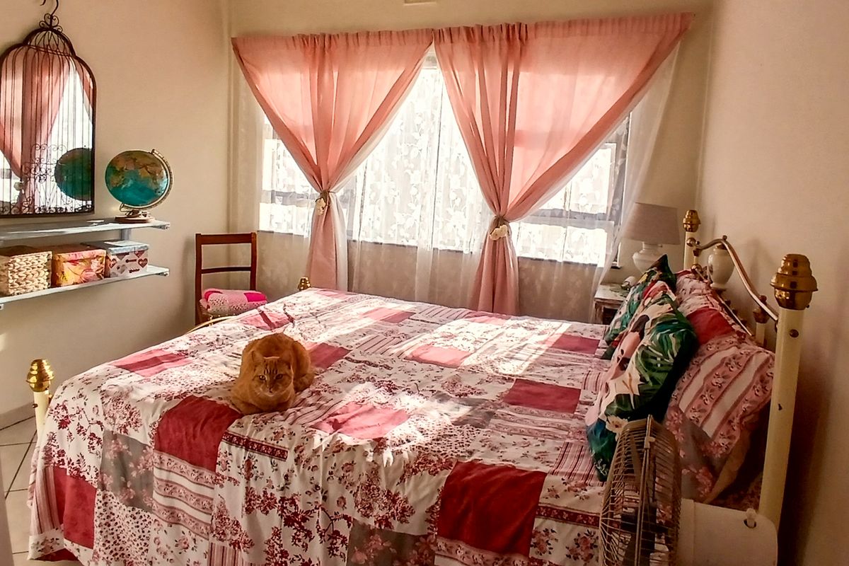 A cozy bedroom featuring tiled flooring and a large window with natural light.