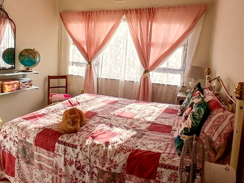 A cozy bedroom featuring tiled flooring and a large window with natural light.