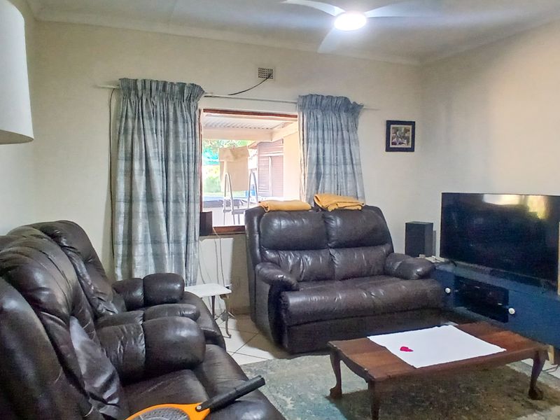 A functional living room featuring tiled flooring, a ceiling fan, and direct access to an outdoor patio area.