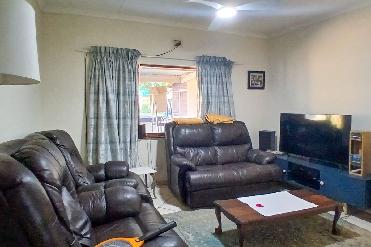 A functional living room featuring tiled flooring, a ceiling fan, and direct access to an outdoor patio area.