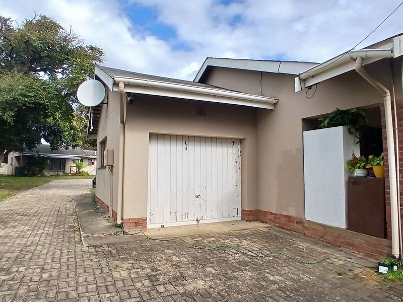 Front exterior view of the property featuring a single garage, brick paved driveway, and established garden surroundings.