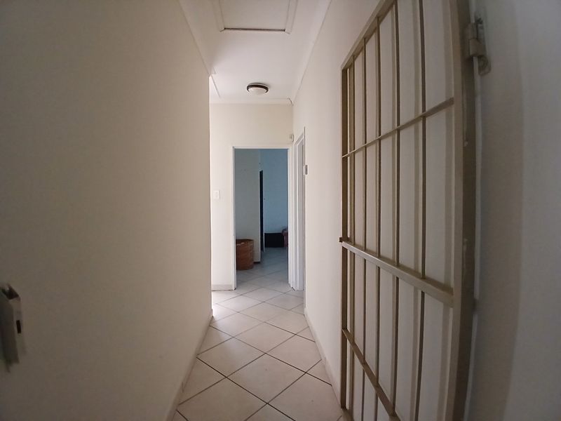 A functional hallway featuring tiled flooring and a fitted security gate, providing access to adjacent rooms.