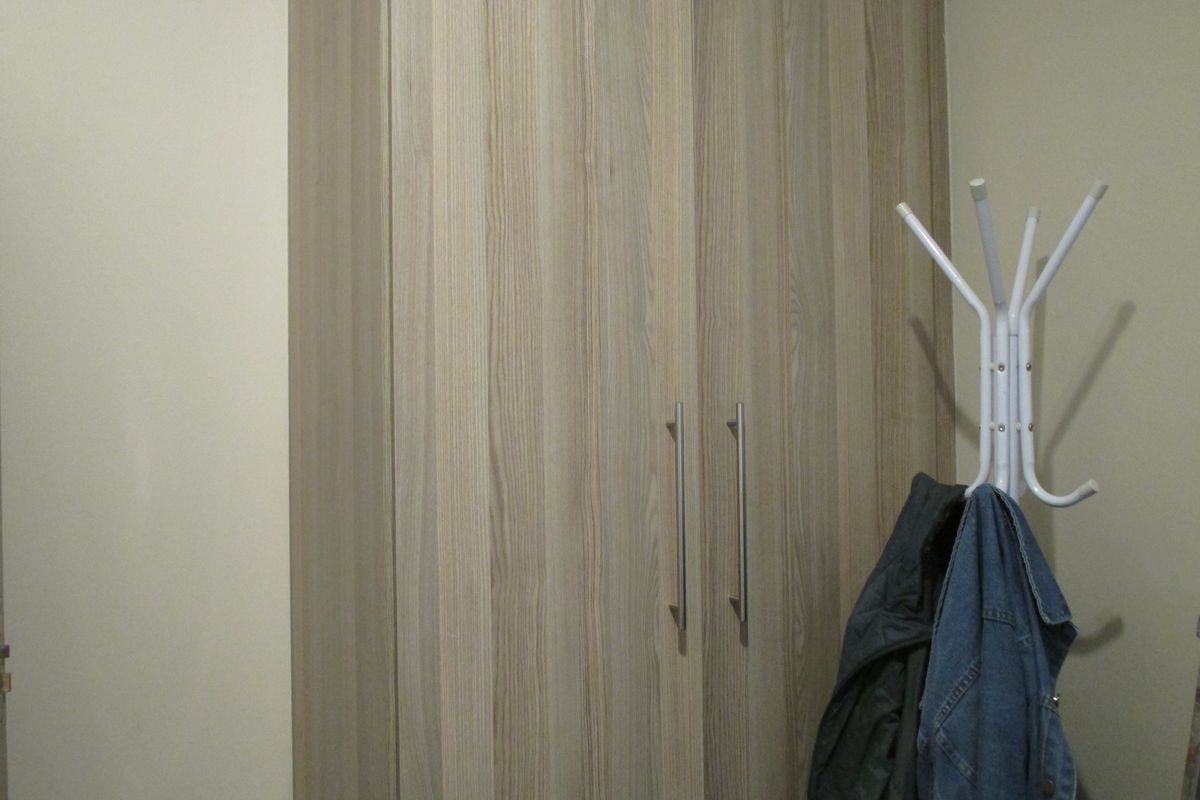 A bedroom featuring a modern wood-grain built-in wardrobe with sleek metal handles.