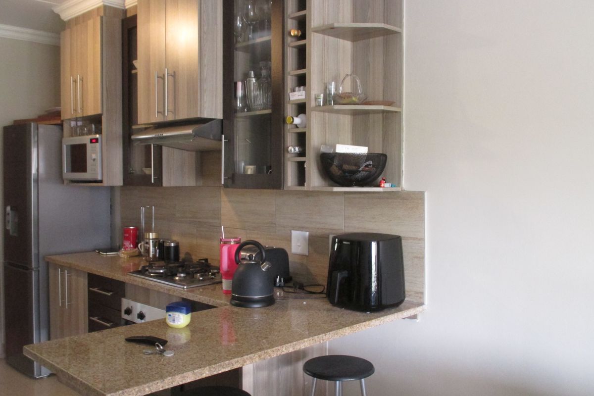 A functional kitchen featuring granite countertops, built-in cabinetry, a gas hob with extractor fan, and a convenient breakfast bar for casual dining.