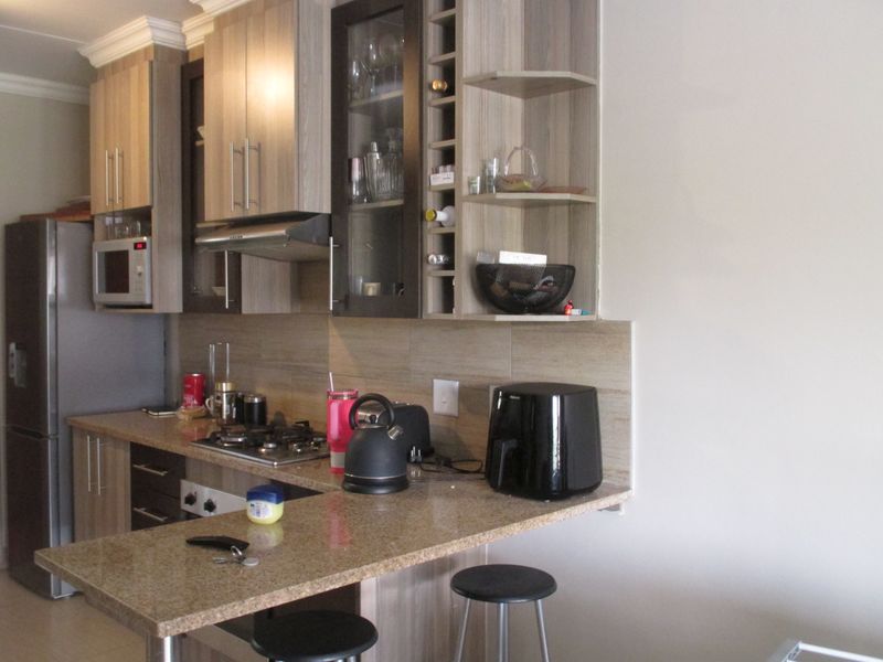 A functional kitchen featuring granite countertops, built-in cabinetry, a gas hob with extractor fan, and a convenient breakfast bar for casual dining.