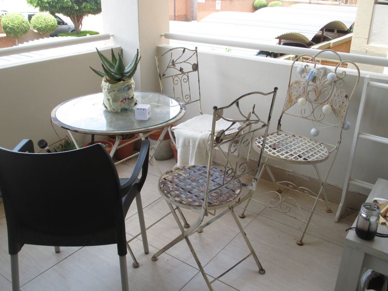 A covered balcony featuring tiled flooring and a metal balustrade, providing an outdoor space for relaxation.