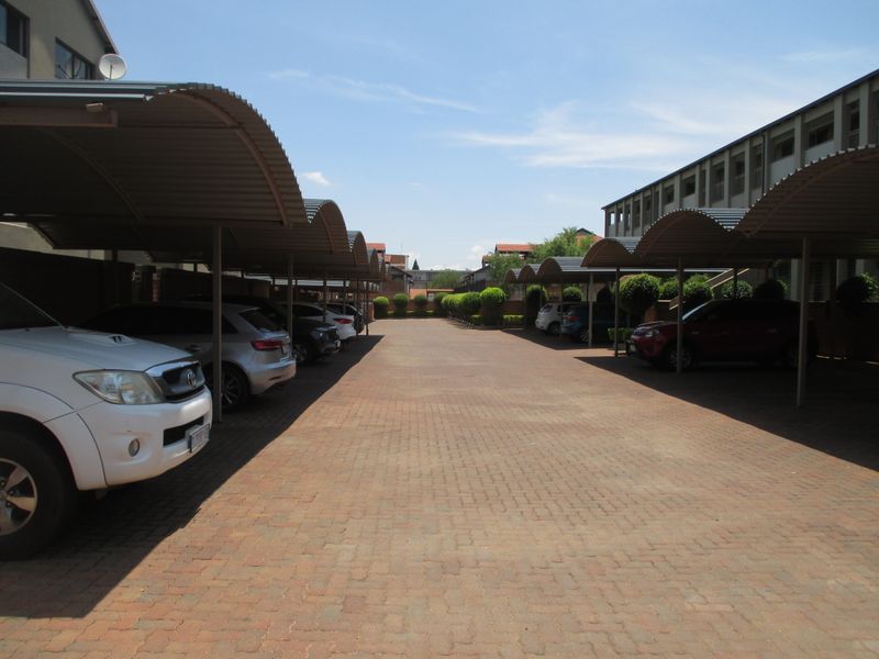 A well-maintained outdoor parking area featuring multiple covered parking bays with metal roofing and paved ground surfaces.