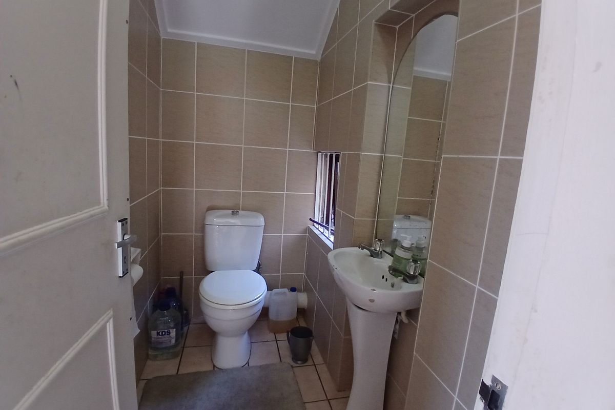 A compact guest bathroom featuring a pedestal basin, toilet, and full-height wall tiling.