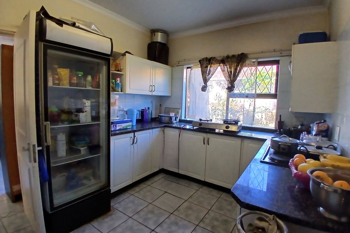 A functional kitchen featuring white cabinetry, dark countertops, tiled flooring, and a window overlooking the exterior.