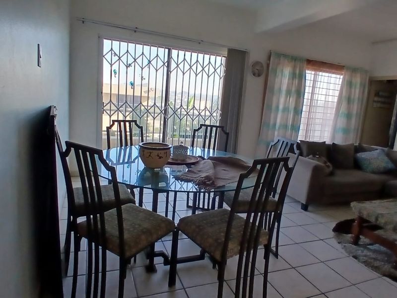 Open plan living and dining area featuring ceramic floor tiles and a sliding glass door with integrated security gate.