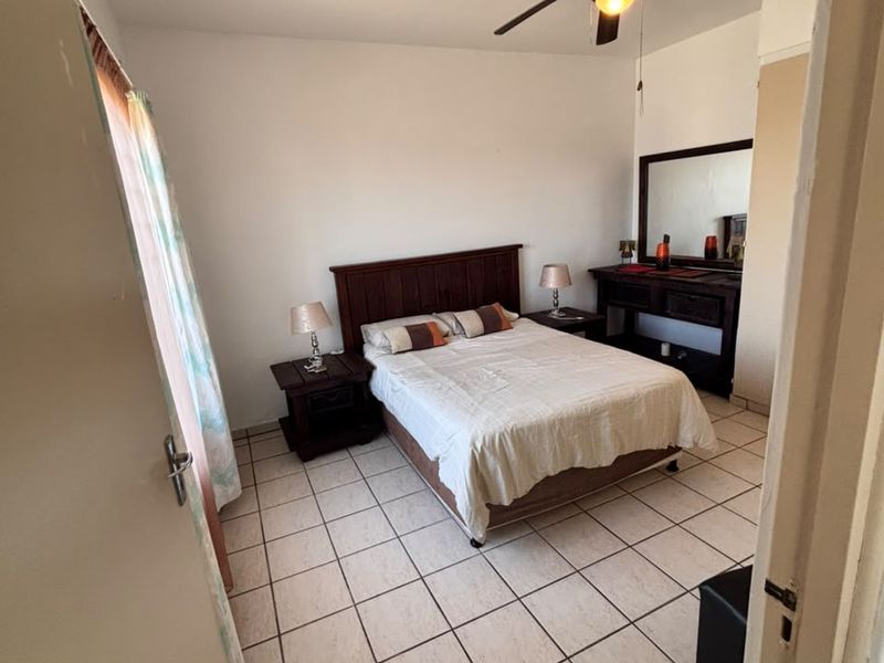 A bedroom featuring ceramic tile flooring and a ceiling fan, offering a functional space with neutral wall finishes.