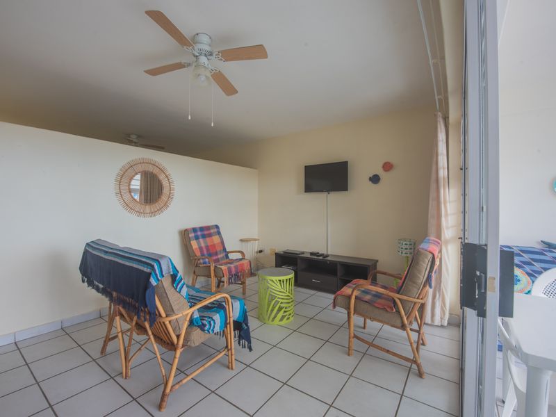 A covered balcony area featuring tiled flooring, a ceiling fan, and sliding glass door access to the main living space.