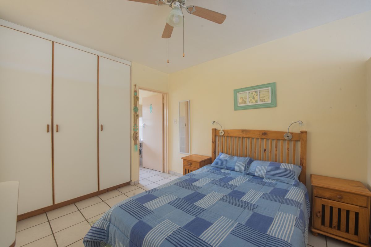 A functional bedroom featuring built-in cupboards, tiled flooring, and a ceiling fan, providing a comfortable and practical living space.