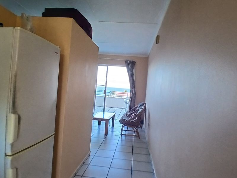 Open plan living area featuring tiled flooring and direct access to a balcony with ocean views.