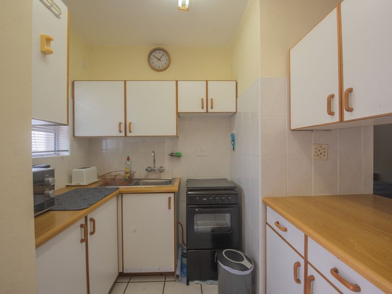 Compact kitchen featuring laminate countertops, white cabinetry, tiled backsplash, and a freestanding stove, offering a functional layout with potential for modern updates.