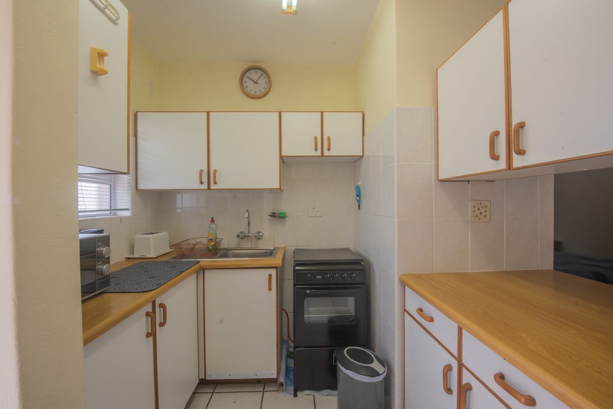 Compact kitchen featuring laminate countertops, white cabinetry, tiled backsplash, and a freestanding stove, offering a functional layout with potential for modern updates.