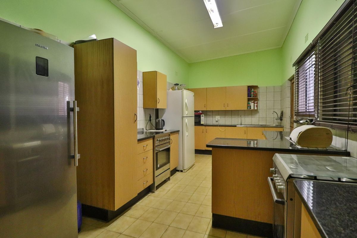 A functional kitchen featuring laminate cabinetry, granite countertops, tiled backsplash, and ceramic flooring, offering a practical layout with integrated cooking appliances.