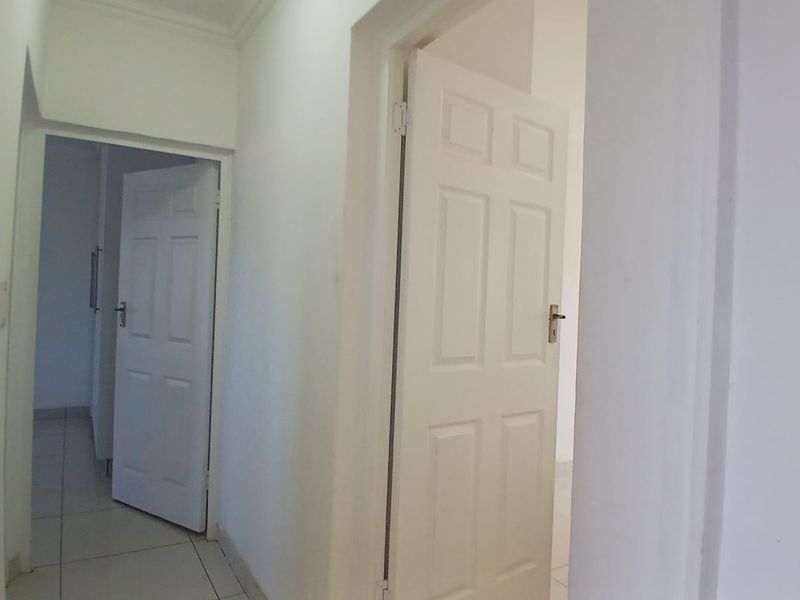 A simple, neutral hallway featuring tiled flooring and white panelled interior doors, providing access to adjacent rooms within the cottage.