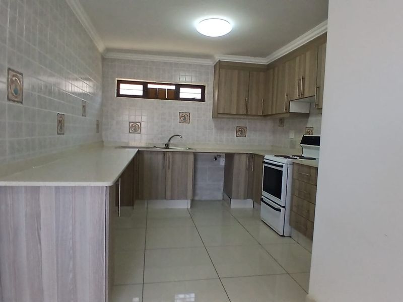 A clean, functional kitchen featuring laminate cabinetry, tiled backsplash, ceramic flooring, and a freestanding stove, offering a neutral space ready for personalization.